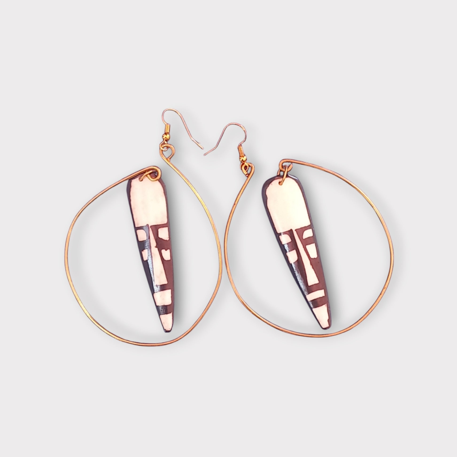 Elegant Kenyan-made earrings combining a natural bone pendant with a bold tribal pattern and a contemporary brass hoop