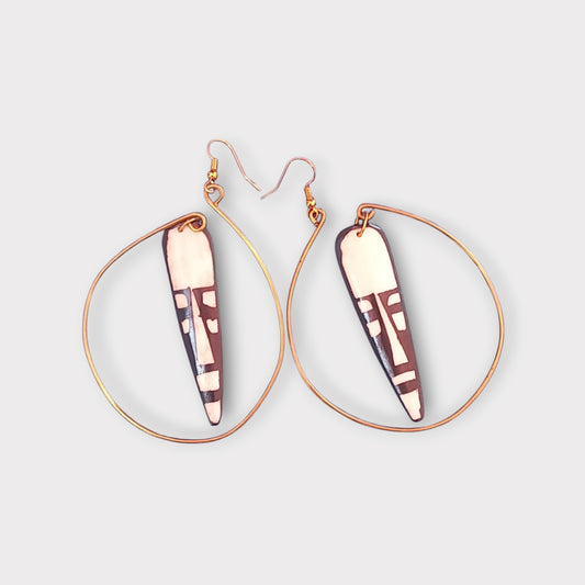 Elegant Kenyan-made earrings combining a natural bone pendant with a bold tribal pattern and a contemporary brass hoop