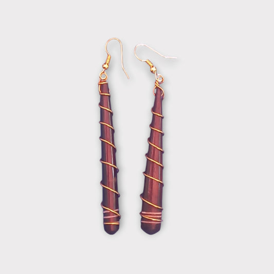 A pair of striking dangle earrings made in Kenya, featuring a slender bone spike adorned with wrapped brass wire.