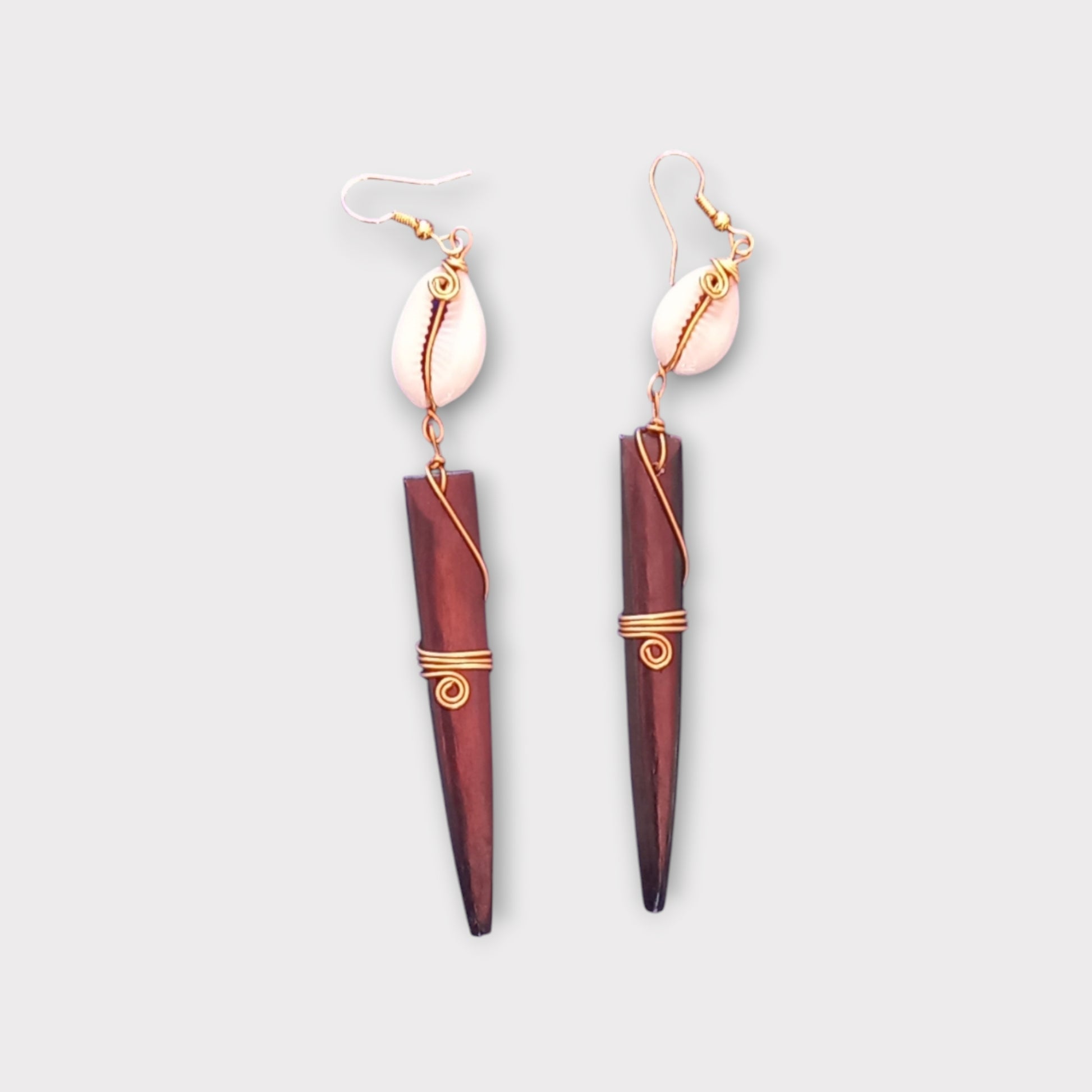 Bold tribal dangle earrings with a small white cowrie shell connected to a striking, spiked bone piece, made in Kenya.