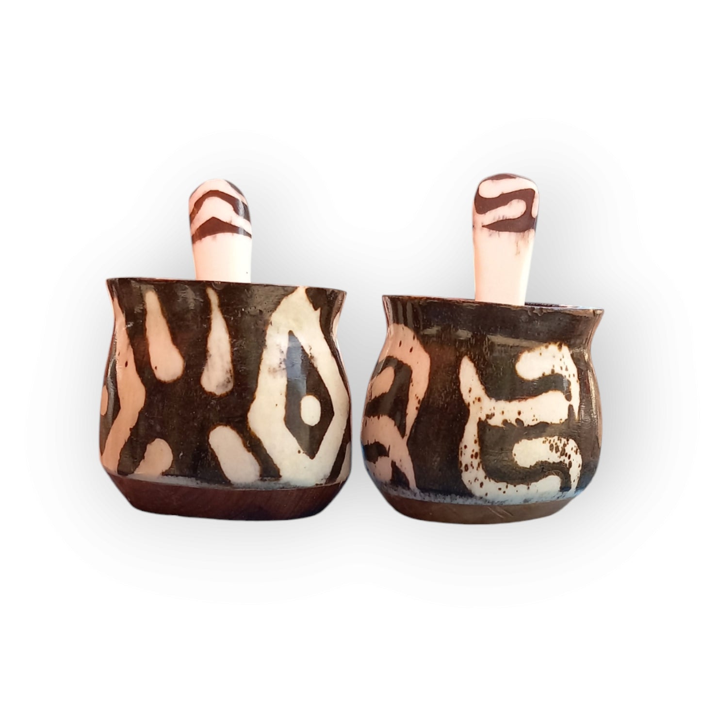 a pair of bone spice pots with a wooden base that has black and white geometric pattern with spoons 