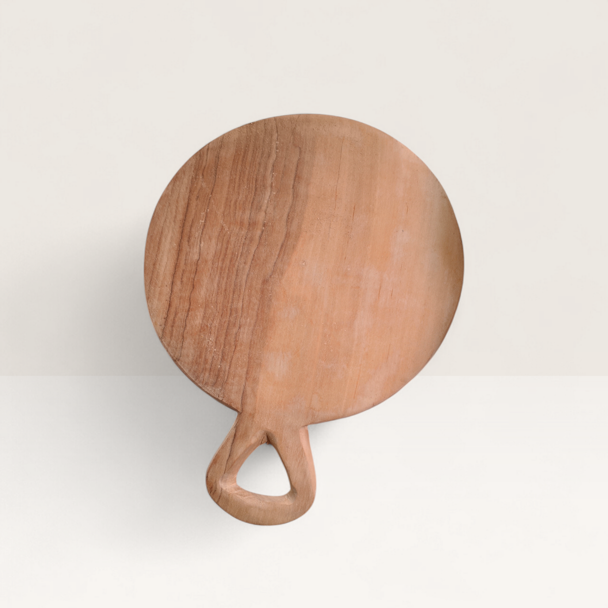 Circular handcrafted Kenyan olive wood chopping board with a triangular handle and swirling natural grain